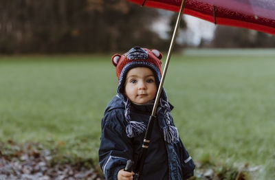 Portrait of girl holding umbrella while standing at park