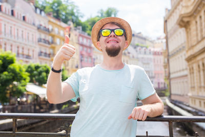 Portrait of young man standing against city