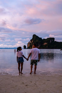 Rear view of women standing at beach against sky