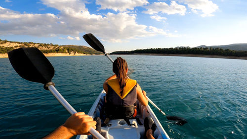 Rear view of woman sitting on boat against sky