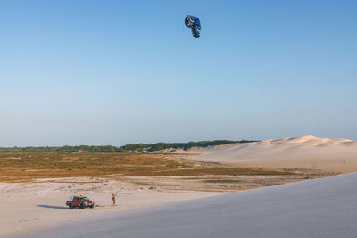 Man kiteboarding at beach against clear sky