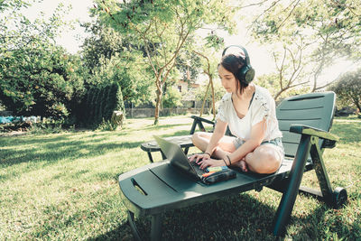 Side view of man using laptop while sitting on field