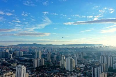 High angle view of city buildings against cloudy sky