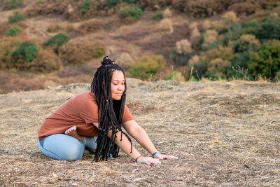 Young woman is sitting in the lotus position and doing yoga on mountain top. 
