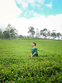 Rear view of woman standing on field against sky