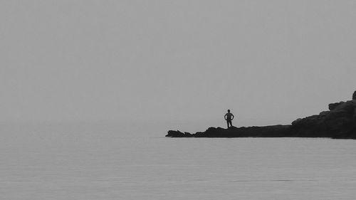 Silhouette men in sea against sky