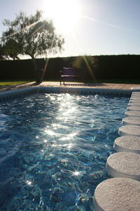 Swimming pool by trees against sky