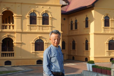 Portrait of smiling mature man standing against building