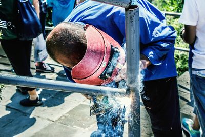 Man welding rods on footpath