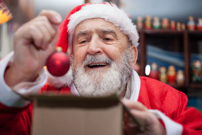 Senior man in santa claus costume sitting at home