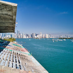 Modern buildings by sea against blue sky