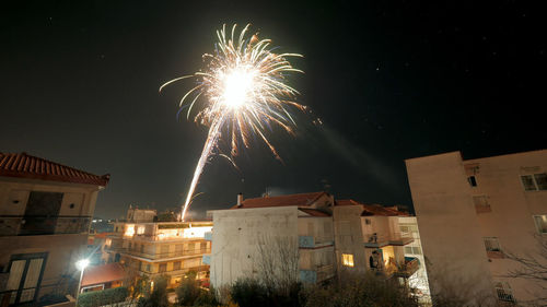 Firework display in city against sky at night