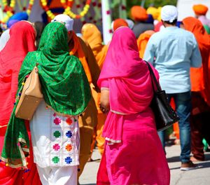 Rear view of people standing outdoors during sunny day