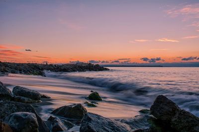 Scenic view of sea against dramatic sky at sunset