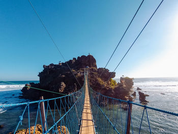 Bridge over sea against clear blue sky