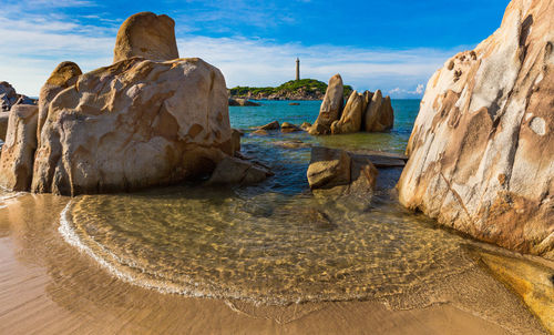 Rock formations on beach against sky