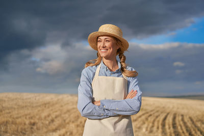 Full length of a smiling young woman standing on field