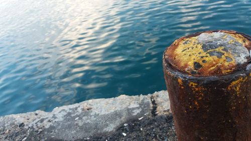 Close-up of rusty metal on rock by sea