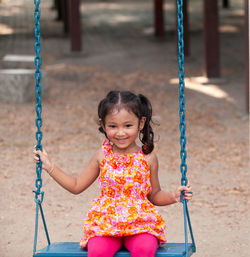 Cute girl sitting on swing at playground