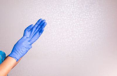 Close-up of hand holding blue over white background