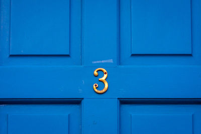 House number 3 on a blue wooden front door