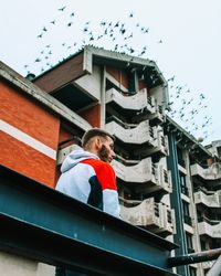 Low angle view of people standing on building against sky