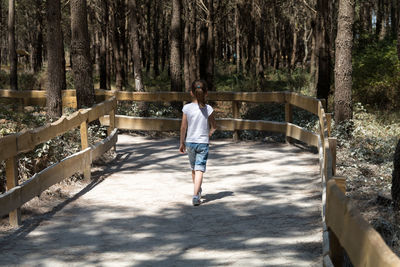 Rear view of girl walking on footpath in forest