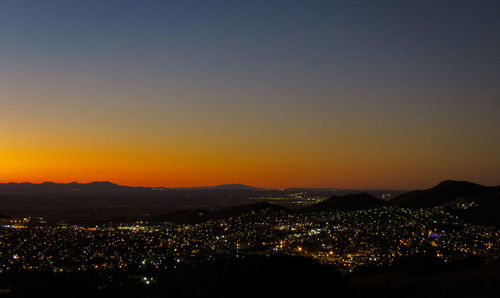 Illuminated cityscape against sky during sunset