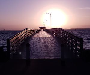 Pier over sea against sky during sunset