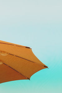 Low angle view of parasol against clear blue sky