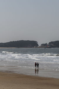 People on beach against clear sky