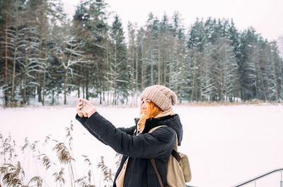 Rear view of woman standing on snow covered field