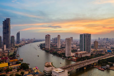 High angle view of river and buildings against sky during sunset