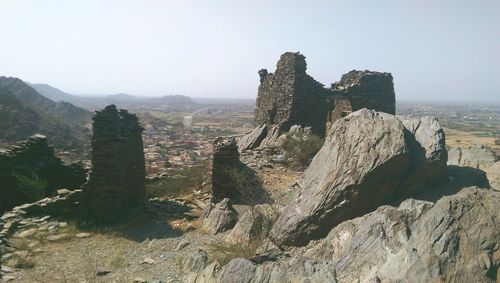 Old ruins and rocks on field against clear sky