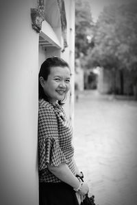 Portrait of smiling woman standing against wall