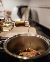 Woman adding white wine on a cooking pot. preparing chicken soup