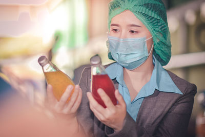 Close-up of woman wearing mask inspecting drinks in factory