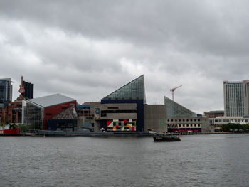 Buildings by river against sky in city