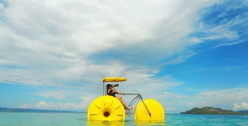 Woman sitting in vehicle on sea against sky