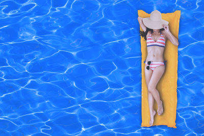 Woman relaxing on raft in swimming pool