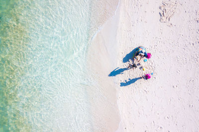 Drone shot of mother and daughters playing on shore at beach during summer