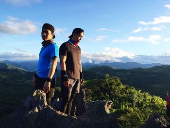 Friends standing on mountain against sky