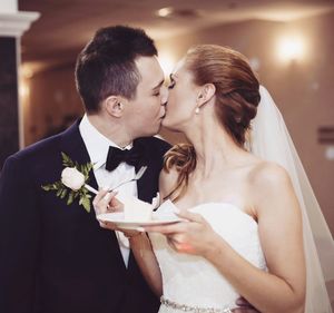 Bridal couple kissing while standing in wedding ceremony