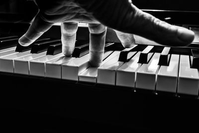 Close-up of person playing piano over black background