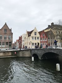 Bridge over river in city against sky