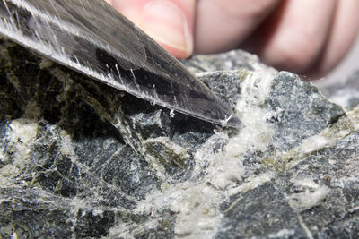 The blade of the knife picks and pulls out the asbestos fibers from the stone.