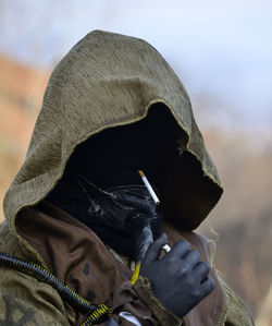 Person wearing costume while holding cigarette and lighter