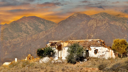 House on mountain against sky during sunset