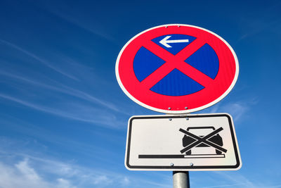 Low angle view of road sign against blue sky