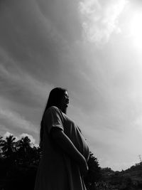 Side view of man looking at camera against sky